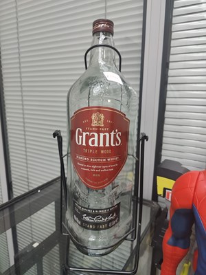 Lot 140 - Grants large glass bottle in swing stand setup and a coin bank